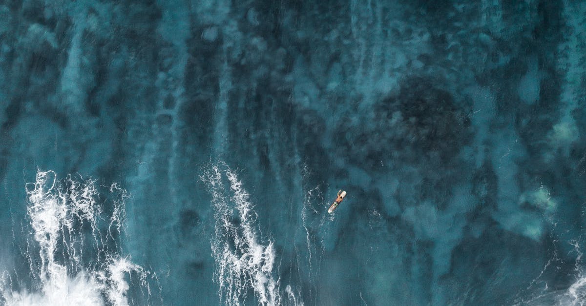 A breathtaking aerial view of a lone surfer navigating the ocean waves.